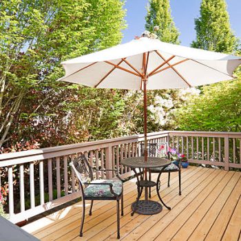 Sunny back deck with table, chairs, and umbrella.
